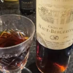 Aged Sauternes wine bottle with dried figs on a wooden table under soft lighting.