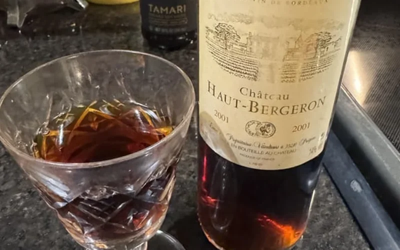 Aged Sauternes wine bottle with dried figs on a wooden table under soft lighting.