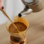 Clear glass carafe filled with steaming blonde roast coffee under natural light.
