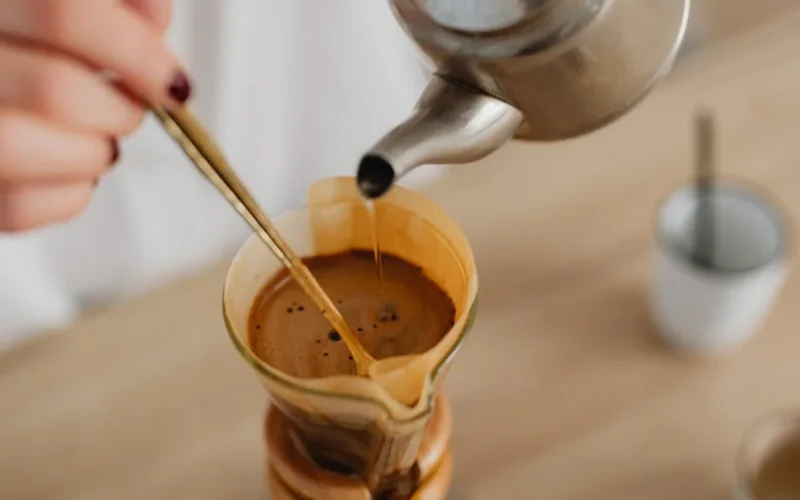 Clear glass carafe filled with steaming blonde roast coffee under natural light.