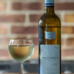 A glass of blouge wine on a wooden table with a sprig of thyme and natural light.