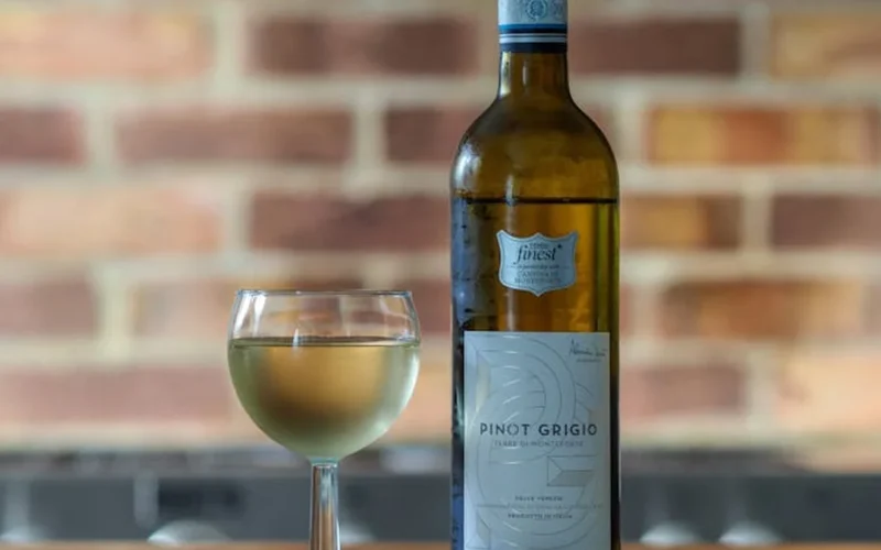 A glass of blouge wine on a wooden table with a sprig of thyme and natural light.