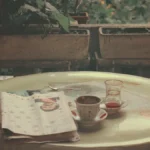 A cozy café table with shared mugs and a mural, bathed in sunset light.