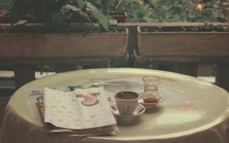 A cozy café table with shared mugs and a mural, bathed in sunset light.