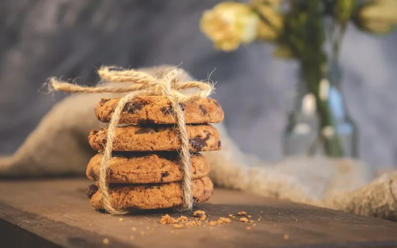 Golden hojicha cookies on wooden board with fresh mint for decoration.