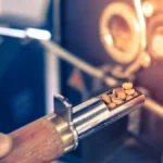 Broken coffee machine leaking metal particles on a marble countertop with disassembled parts nearby.