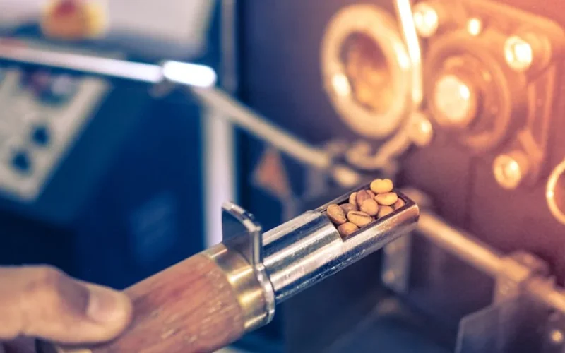 Broken coffee machine leaking metal particles on a marble countertop with disassembled parts nearby.