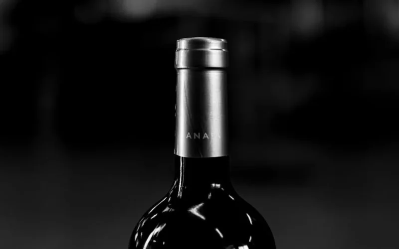 Aged wine bottle surrounded by dried herbs and wooden barrel, evoking a mature vintage's aroma and depth.