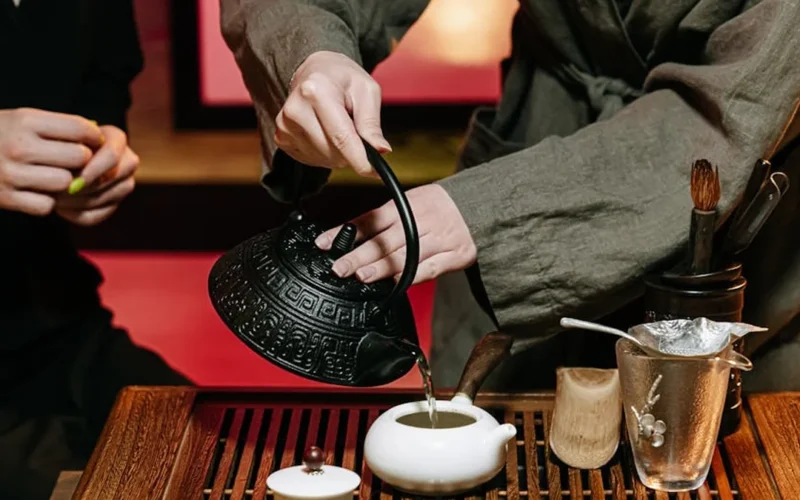 Pakistani designer enjoying tea in a traditional Indian home with vintage crockery and steam rising from a clay pot.