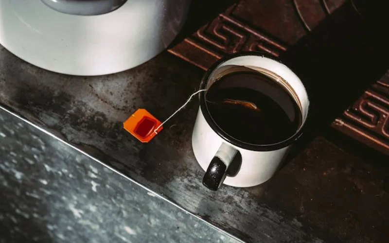 Golden rooibos tea steaming in a clay pot on wooden shelves in a sunlit South African kitchen.