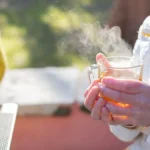 Crumpled raw puer tea leaves in a clay teapot with rising steam under warm lighting.
