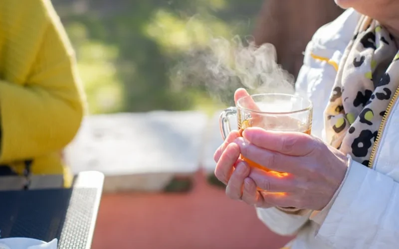 Crumpled raw puer tea leaves in a clay teapot with rising steam under warm lighting.