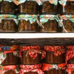 Fermented wine lees in a glass jar with chocolate and wine bottles on a wooden table.