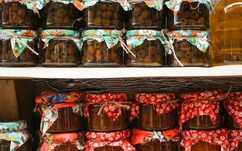 Fermented wine lees in a glass jar with chocolate and wine bottles on a wooden table.