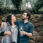 Vintage wine barrel in a rustic vineyard with family portrait and modern tasting room in the background.