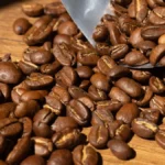 Charcoal kamado roasting coffee beans with steam rising in warm golden light.