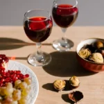 Rustic wooden table with wine glass, grapes, and vintage Chianti map under warm light.