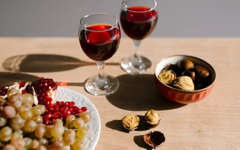 Rustic wooden table with wine glass, grapes, and vintage Chianti map under warm light.