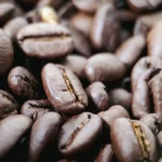 Dark coffee beans with center line char on wooden table under golden light.