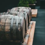 A rustic cellar with aged wine barrels and bottles under a golden sunset light.
