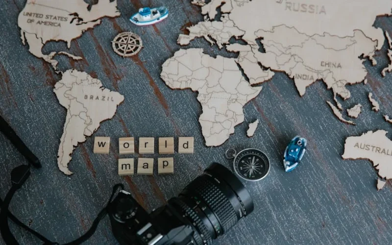 Steaming decaf coffee cup with price tag on wooden table next to Colombia map with red pins.
