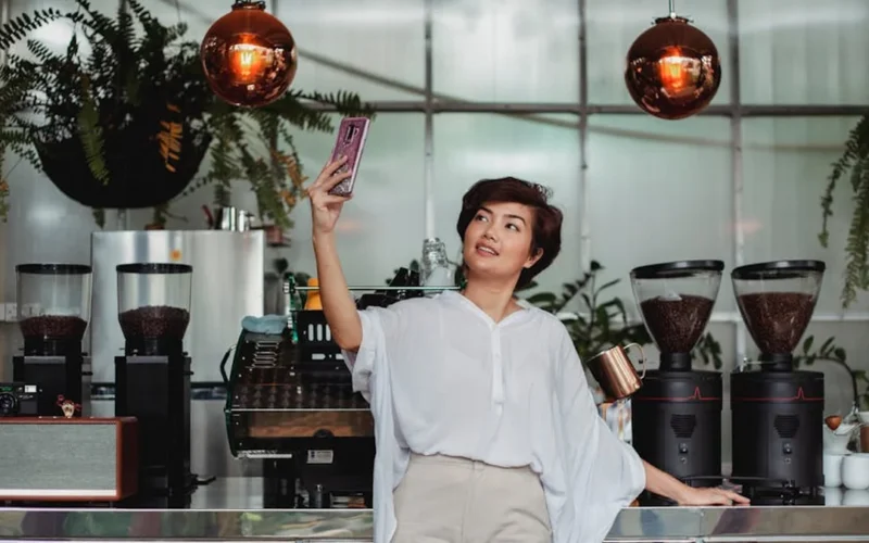 Coffee influencer gestures over coffee cup in modern café with natural light