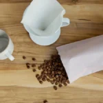 A steaming pour-over coffee cup on a wooden table with sunlight streaming through a curtain.