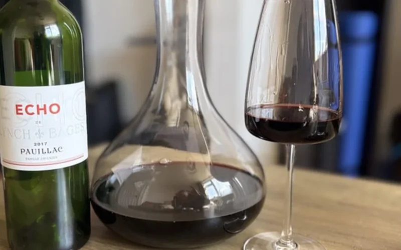A dark red wine decanter surrounded by aged wood and leather under soft lighting.