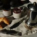 A traditional Finnish coffee table with pastries, sandwiches, and a steaming coffee cup under warm morning light.