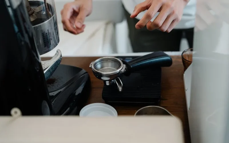 High-end espresso machine with 49mm puck in use, steam rising, warm lighting highlights polished surface.