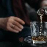 Harrison Ford pours Glenmorangie whiskey into a crystal glass at Sunset Tower with golden light reflecting off the liqui