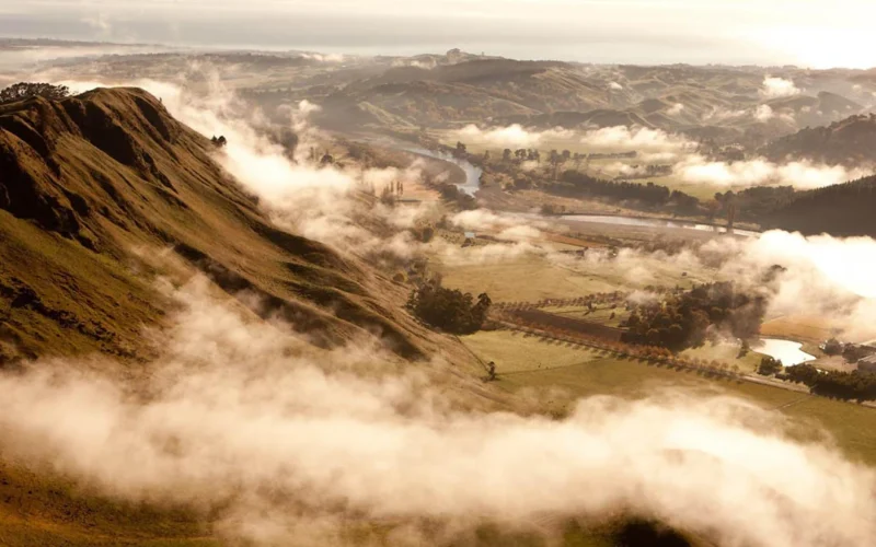 Sunset over Hawke’s Bay vineyards with gravel soils and wine bottles in the foreground.