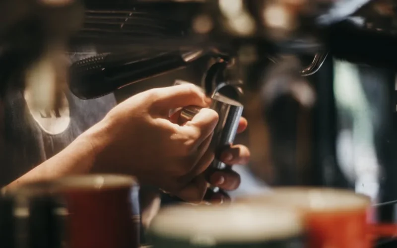 A high-end portable espresso machine brewing rich espresso into a dark cup on a clean surface.