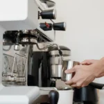 A modern coffee roaster machine with digital controls and coffee beans nearby under natural light.