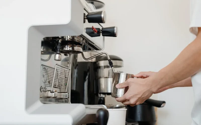 A modern coffee roaster machine with digital controls and coffee beans nearby under natural light.