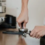 Traditional coffee grinding process using a mortar and pestle in a rustic kitchen setting.