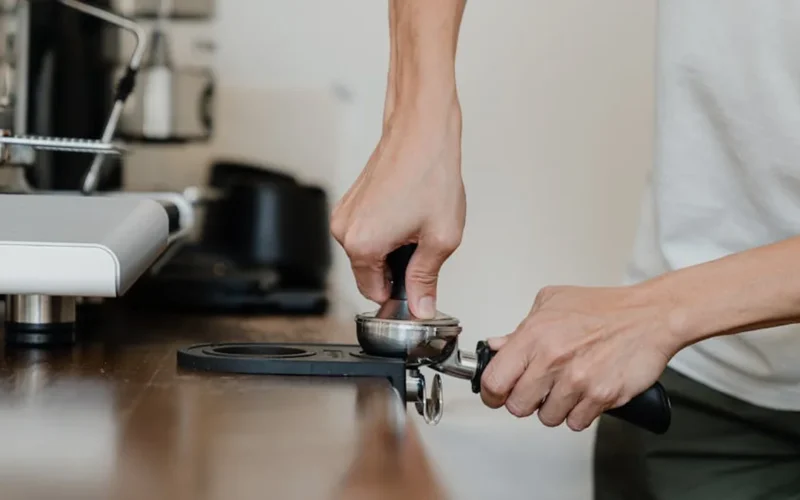 Traditional coffee grinding process using a mortar and pestle in a rustic kitchen setting.