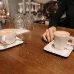 Barista creating latte art on milk foam in a cozy café setting with warm lighting.