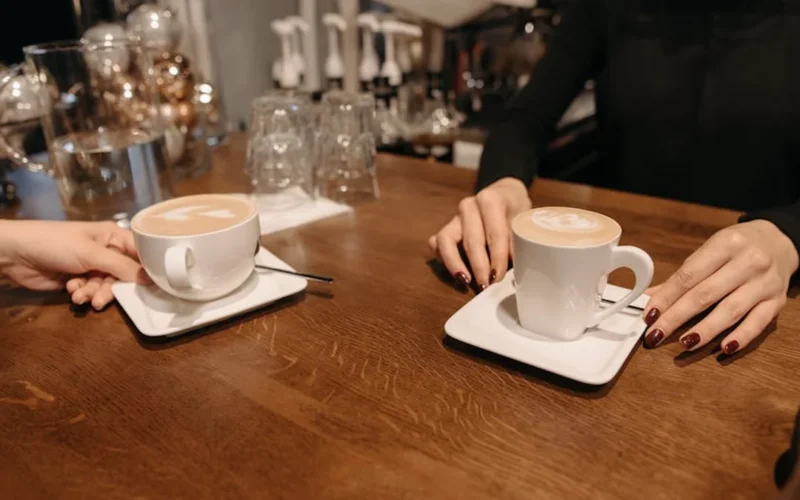 Barista creating latte art on milk foam in a cozy café setting with warm lighting.