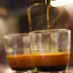 Artisan roasting coffee beans in high-end machine with steam and golden lighting.