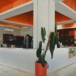 Modern café interior with minimalist design, steam rising from coffee, soft lighting highlights coffee beans and furnitu