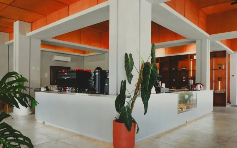 Modern café interior with minimalist design, steam rising from coffee, soft lighting highlights coffee beans and furnitu