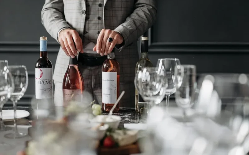 A rustic wine tasting room with a plate of refried beans and flan beside a glass of red wine under warm lighting.