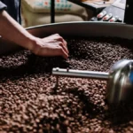 Coffee roaster in action with steam rising from beans during the roasting process.