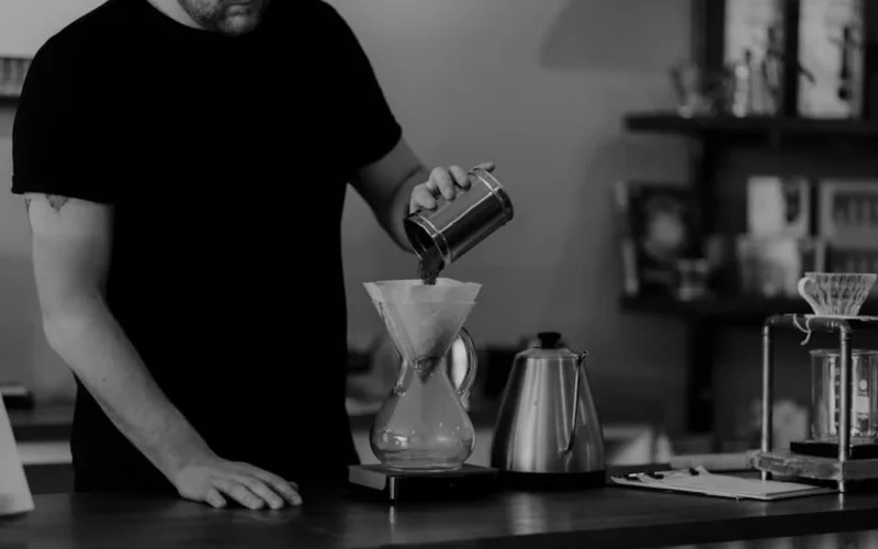 Binocular dripper brewing two coffee streams into separate cups with soft lighting and modern bar setup.