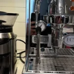 Black PID coffee machine pouring coffee into white ceramic mug under soft lighting.