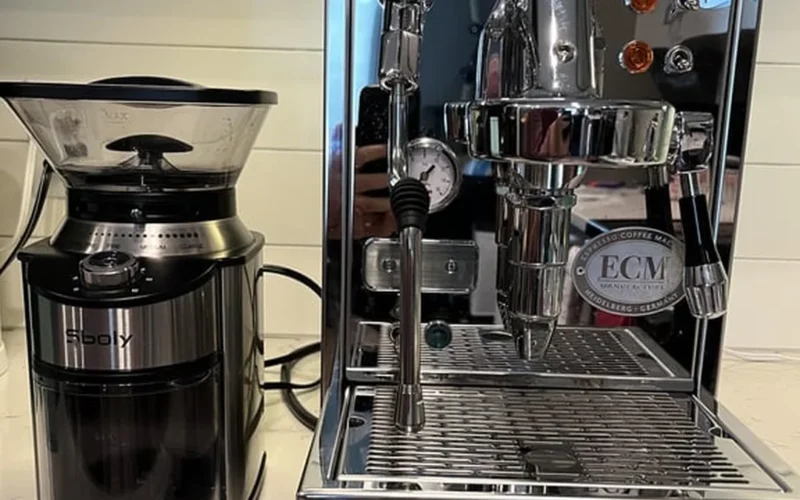 Black PID coffee machine pouring coffee into white ceramic mug under soft lighting.