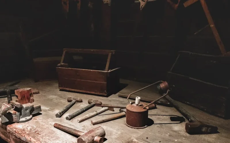 Vintage coffee mill grinding beans in a sunlit workshop with wooden shelves and warm lighting.
