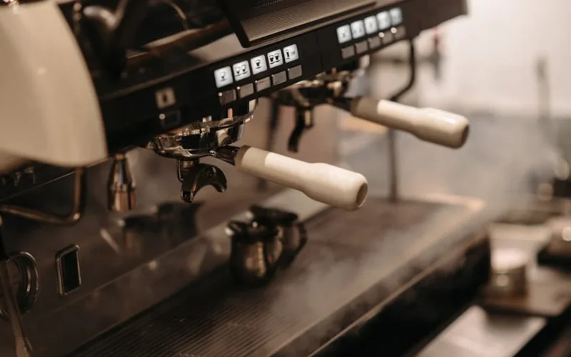 Rancilio Silvia espresso machine with PID control kit in use, steam rising from portafilter under warm lighting.