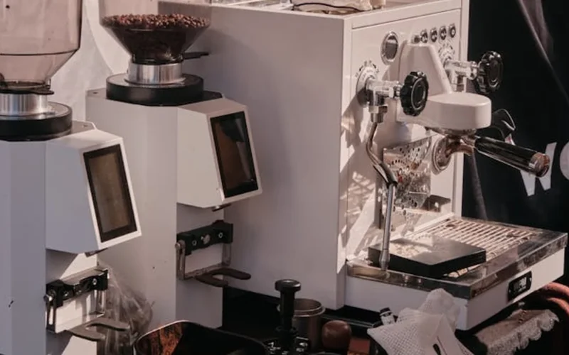 Large industrial coffee grinder in a factory setting with steam rising from the grinding process.